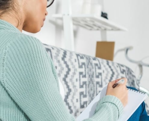 young woman in apartment, making notes on how to negotiate rent