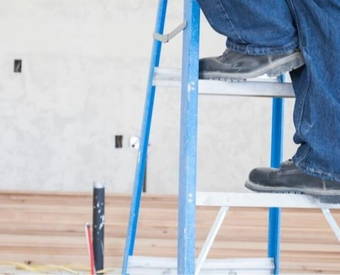 contractor on ladder, working on major home repair costs