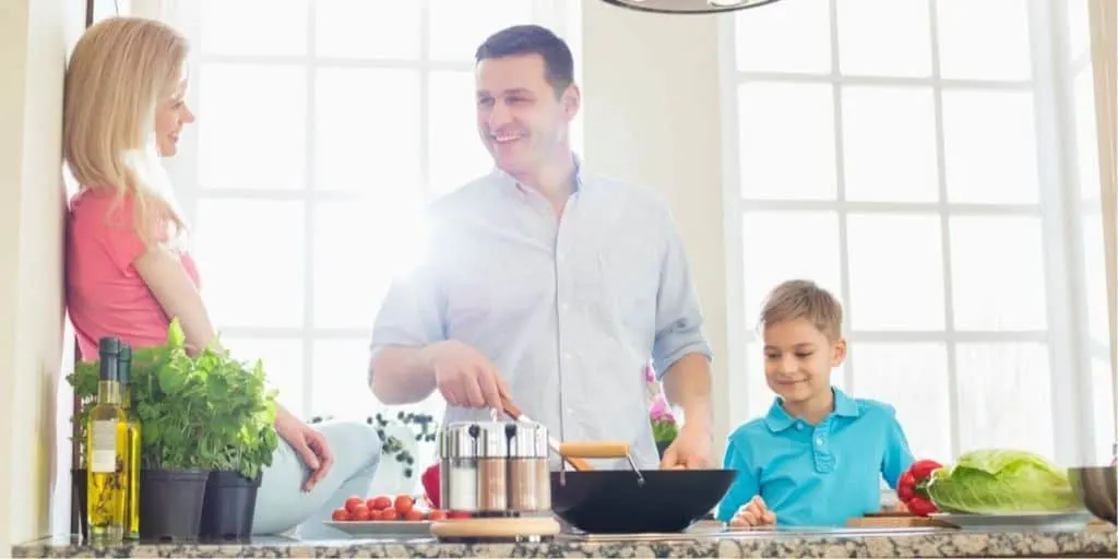 family in kitchen, all cooking together a meal to eat at home instead of eating out