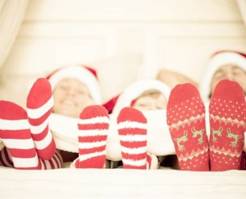 family laying down in bed, with Christmas socks on