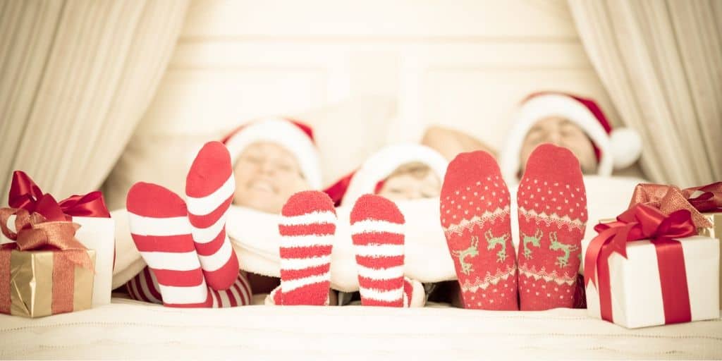 family laying down in bed, with Christmas socks on