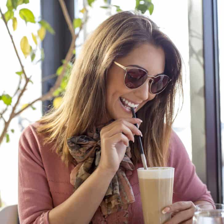 woman in sunglasses smiling sipping on free birthday latte