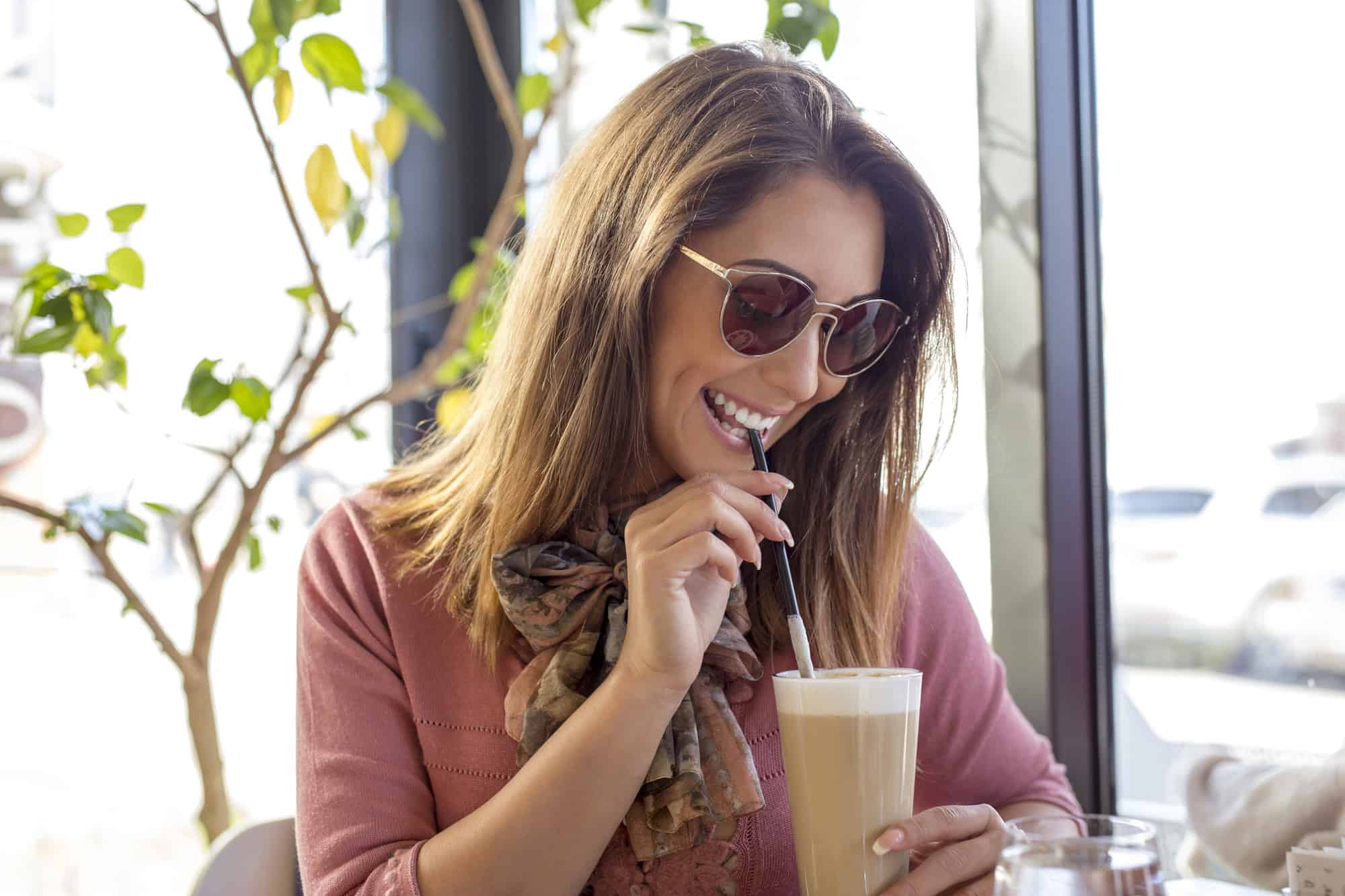 woman in sunglasses smiling sipping on free birthday latte