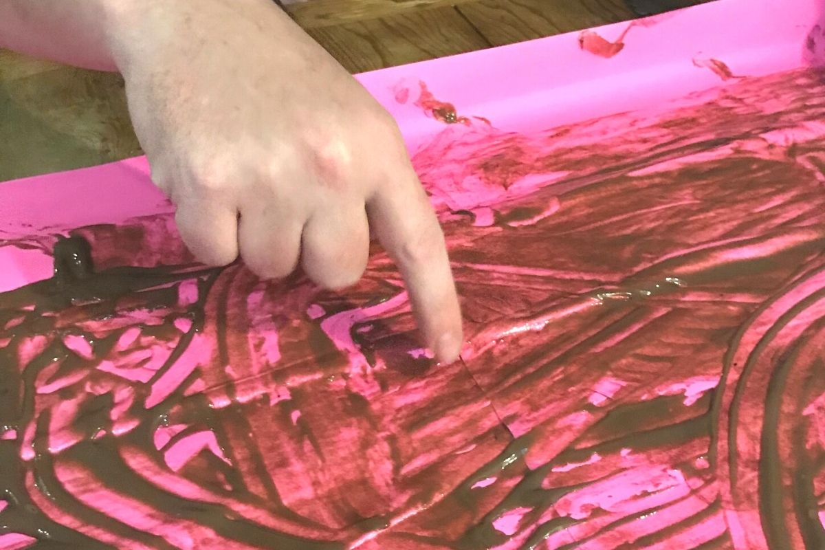 finger drawing in pudding on pink fluorescent paper