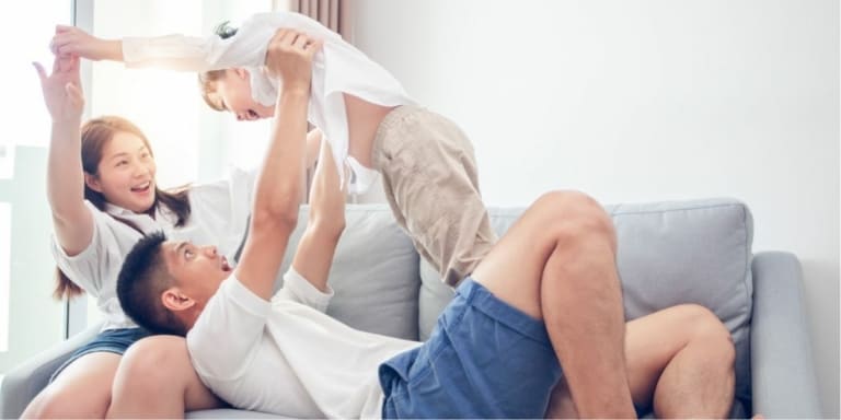 young asian family playing on the couch, not thinking about recessions