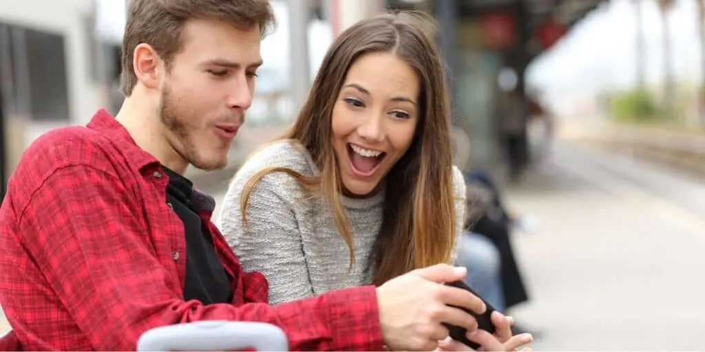 couple sitting on train bench, shocked by awesome relationship app