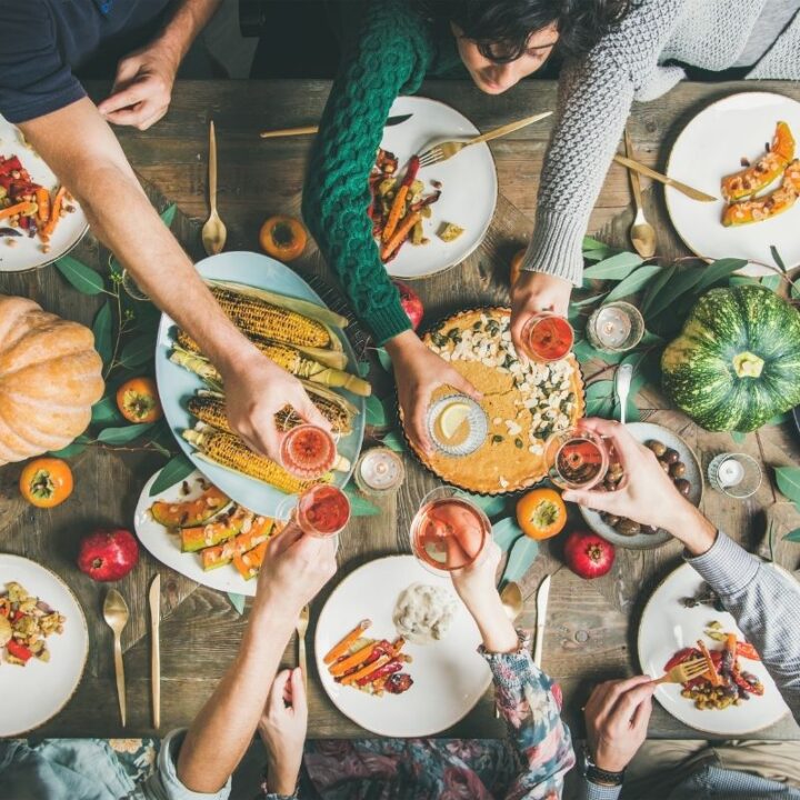 hands around a Thanksgiving meal table reaching for food