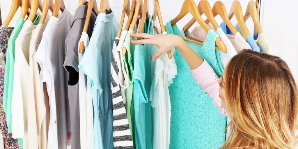 woman going through her closet of teal, blue, and white clothes