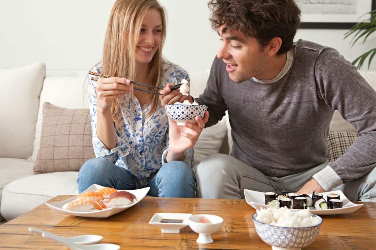 guy and gal eating grocery store sushi at coffee table