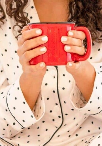 woman smiling, holding mug of hot cocoa for what to do when you're bored without friends