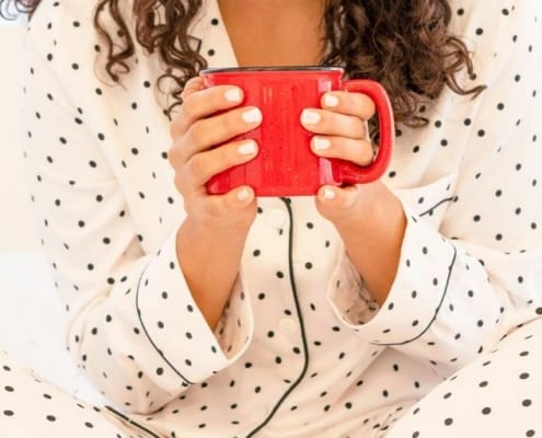 woman smiling, holding mug of hot cocoa for what to do when you're bored without friends