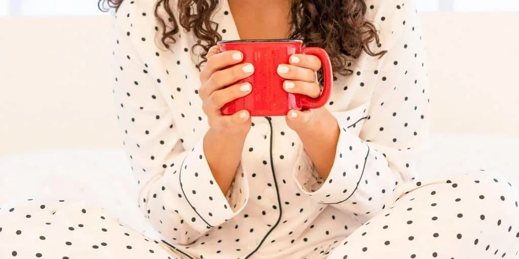 woman smiling, holding mug of hot cocoa for what to do when you're bored without friends