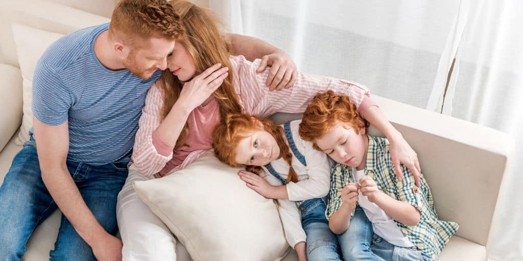 red-headed family sitting on couch, thankful for finding financial help for families