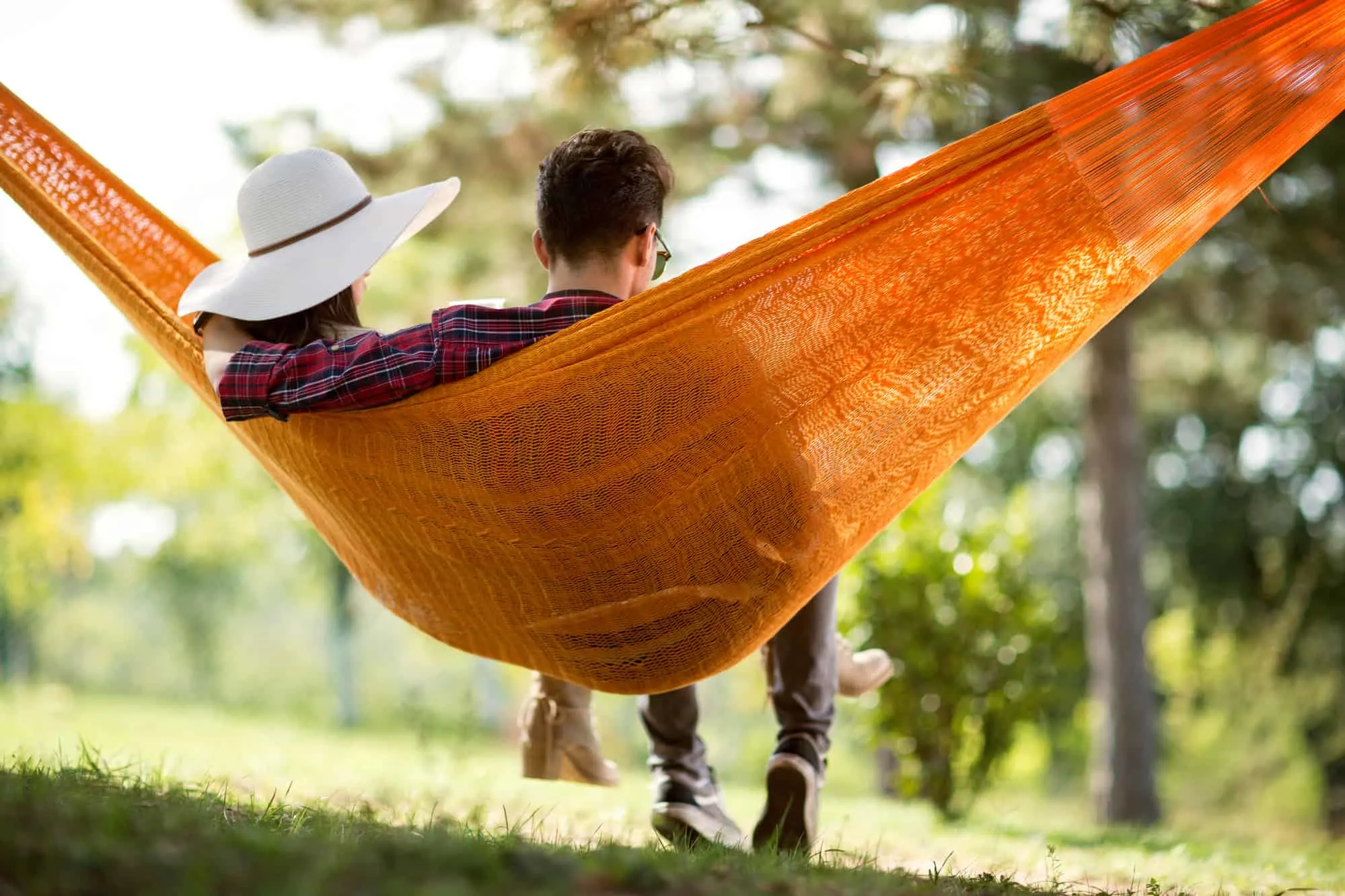 young couple enjoying at home date night in an orange hammock in their backyard