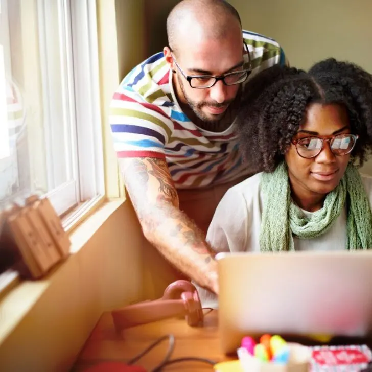 couple looking at computer, smiling, at kitchen table