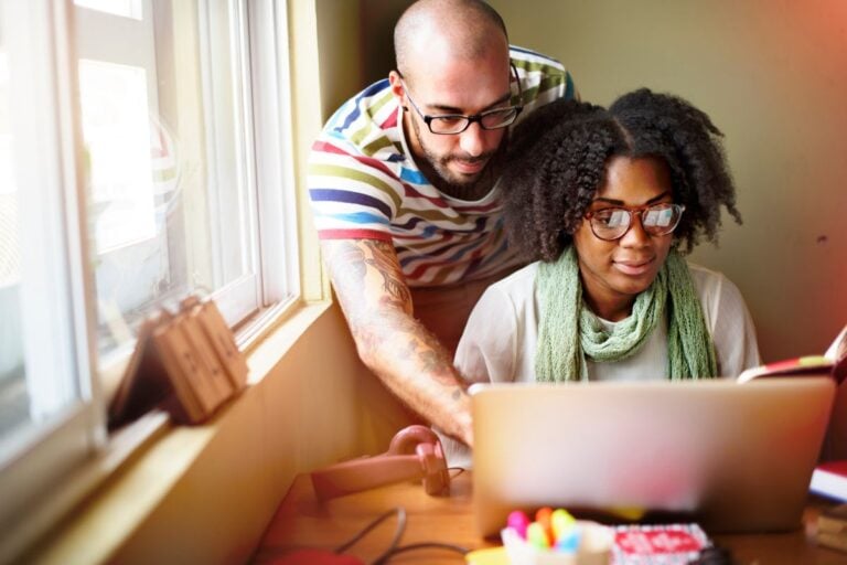 couple looking at computer, smiling, at kitchen table