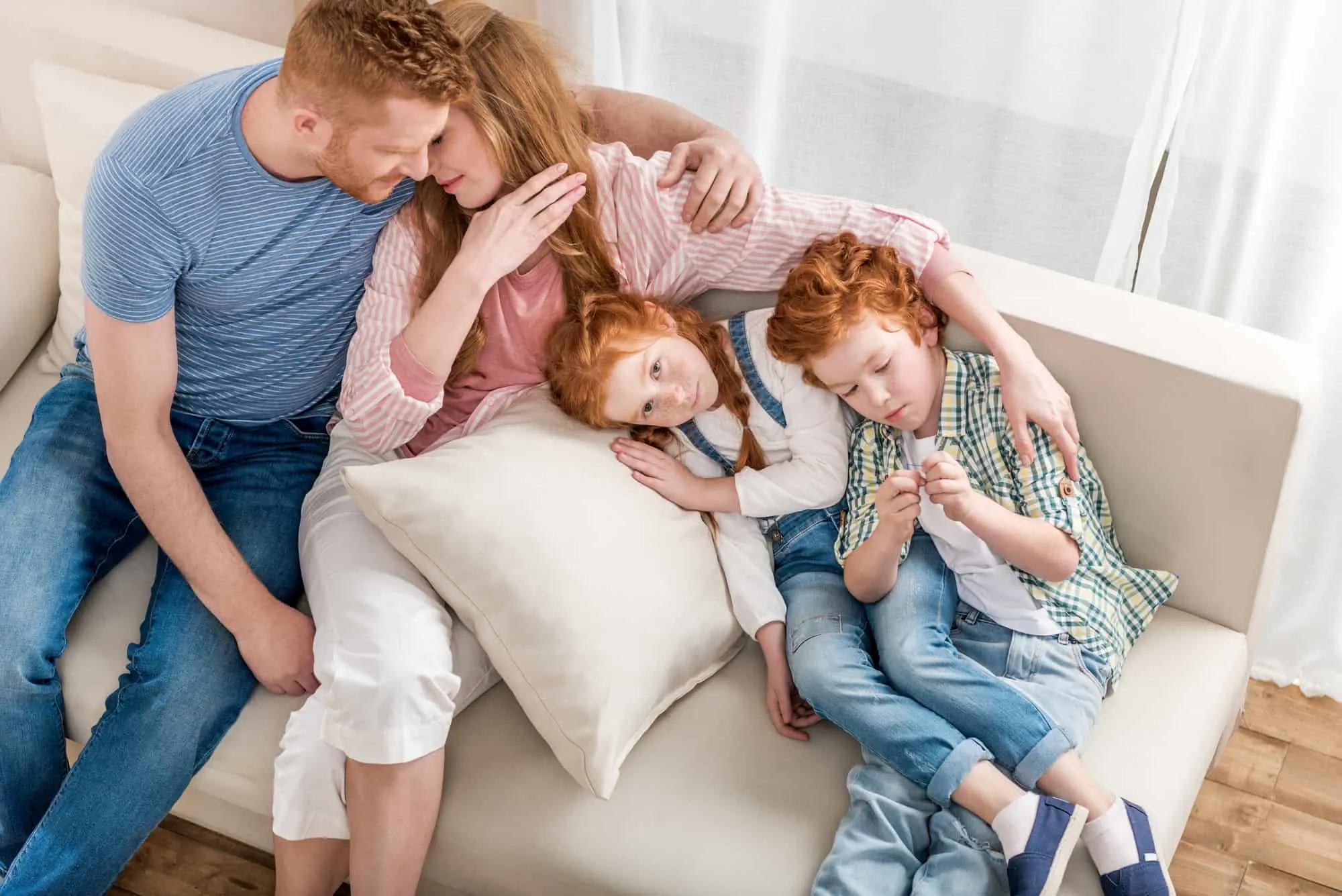 family sitting on couch, mother thinking about protecting everyone with a life insurance policy