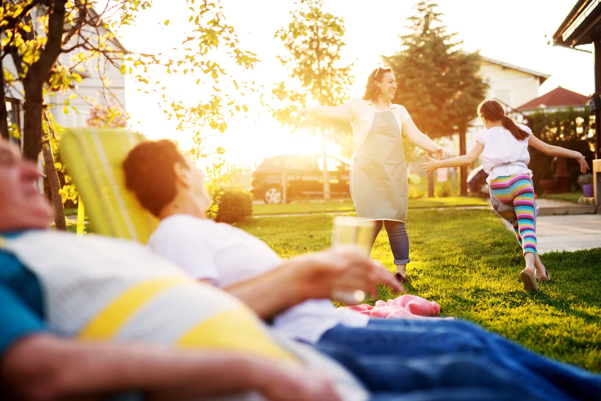 family out back, cheerful woman playing with daughter, father thinking about whether or not to get a life insurance policy to protect everyone