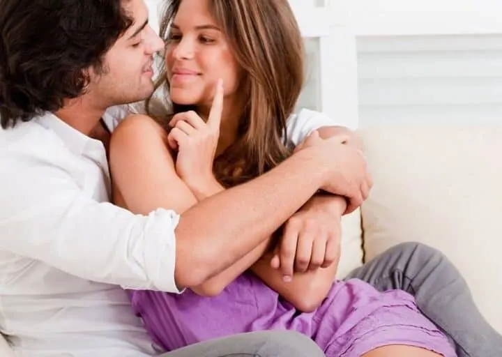 couple cuddling on couch looking expectantly at each other about a free date idea