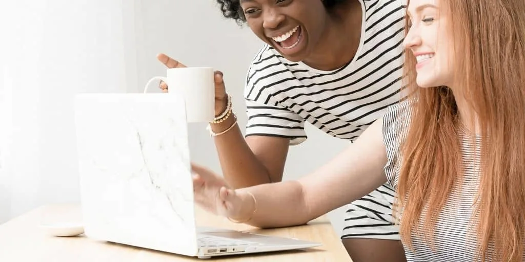 coworker girls working together at desktop, thinking of inexpensive thank you gifts to buy from computer