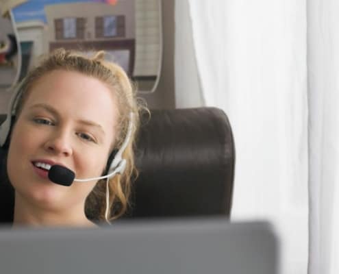 woman with headset at home desk, teaching english online with education first