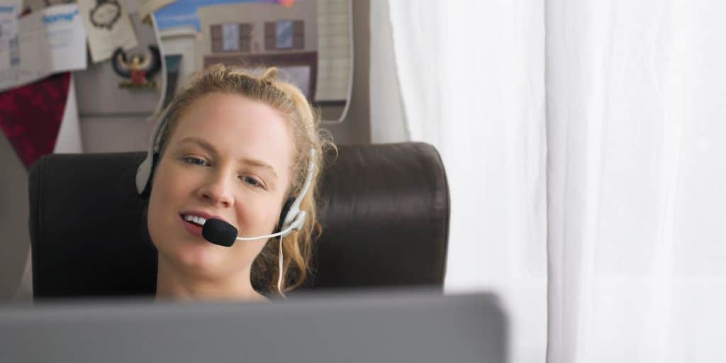 woman with headset at home desk, teaching english online with education first