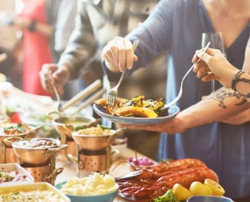crowd of people around a festive table of food, serving winter meals for a crowd to themselves