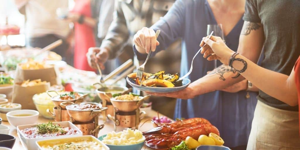 crowd of people around a festive table of food, serving winter meals for a crowd to themselves