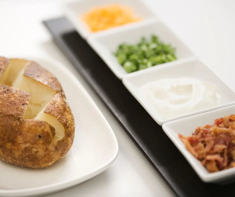 baked potato bar with cheese, scallions, sour cream and bacon as an easy winter meals for a crowd