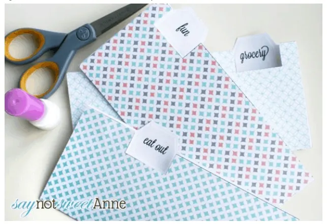 three cash envelopes with blue patterns on desk with scissors and marker