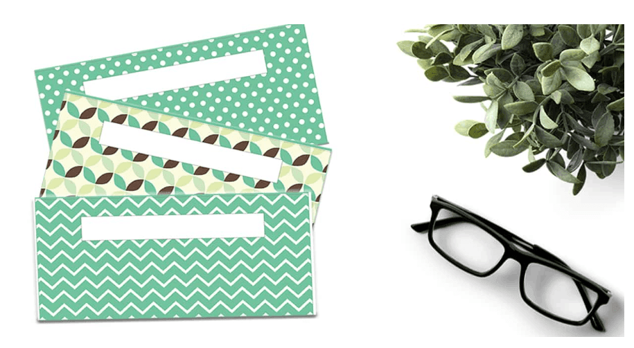 3 green patterned envelopes for cash with glasses on white background
