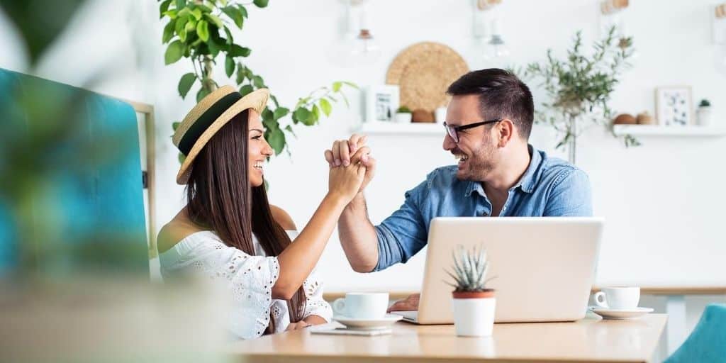 married couple slapping each other 5 in front of laptop, taking free online marriage counseling course