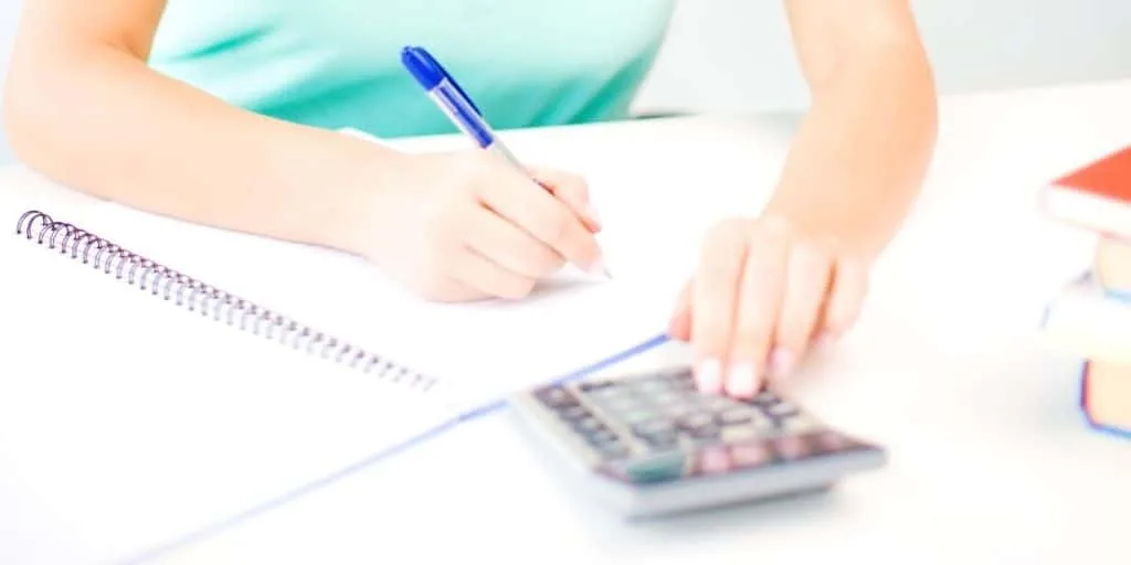 woman in blue shirt at desk, working on budgeting techniques and strategies with calculator
