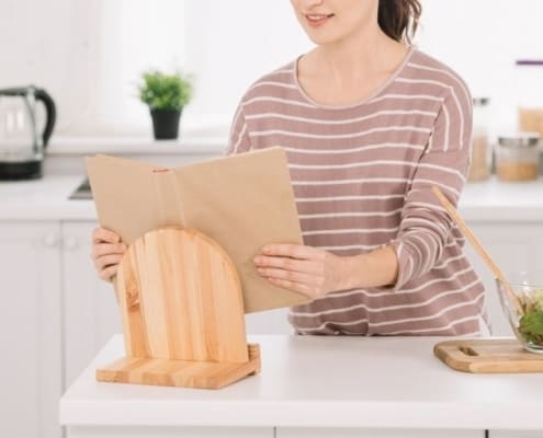 woman in kitchen using recipe stand and recipe binder printables as part of her recipe binder system