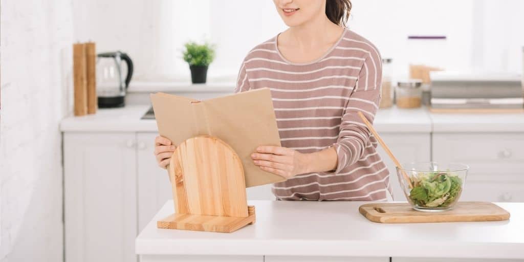 woman in kitchen using recipe stand and recipe binder printables as part of her recipe binder system