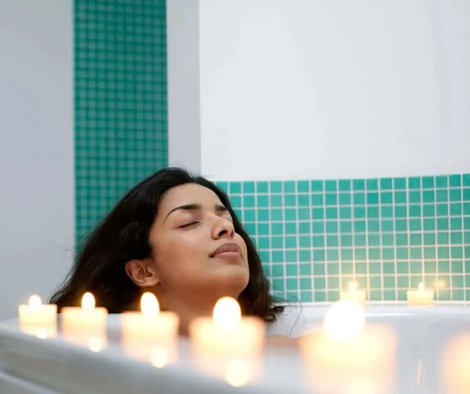woman sitting back, relaxing in bath tub surrounded by candles as a small daily rewards