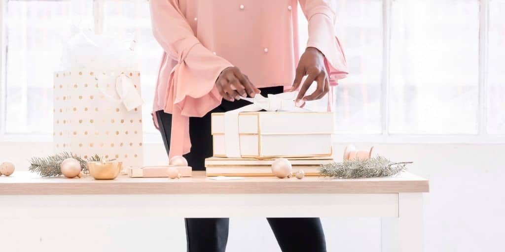 woman wrapping gifts at a table, staying within her Christmas budget pdf