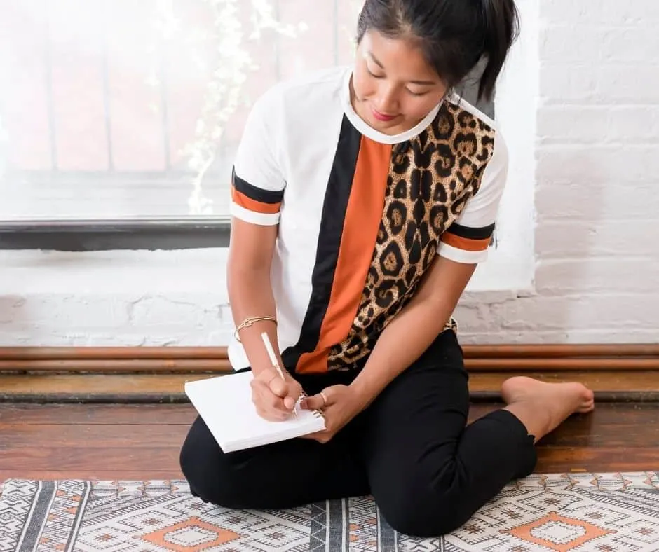 Asian woman doing abundance mindset exercises in her journal 