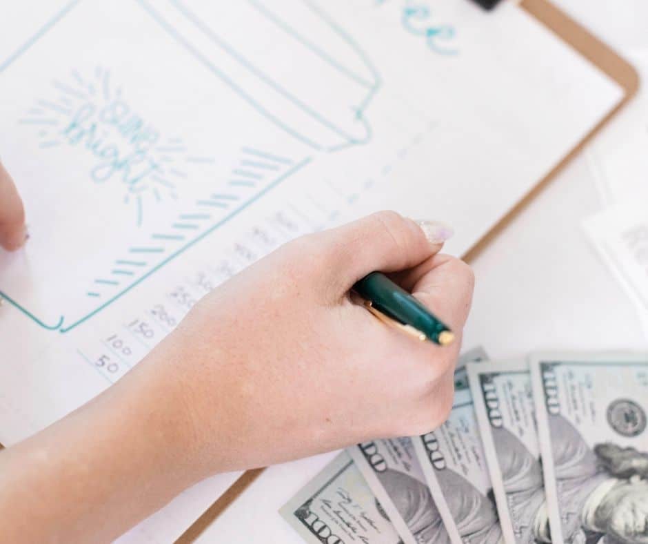 woman working on her spending audit from the previous year, with clipboard and money by her side