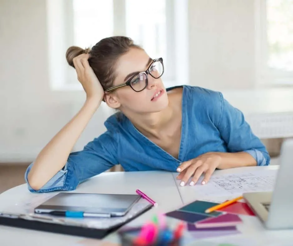 woman looking reflectively at her spending at desk, wondering how to train yourself to spend less money