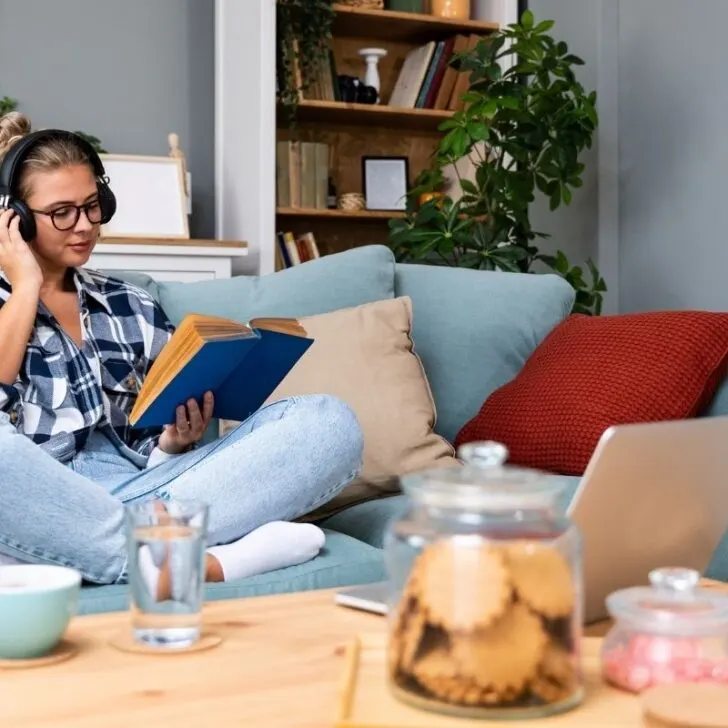 woman with glasses on couch, reading