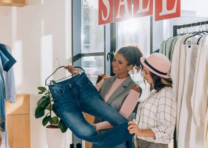 three women shopping a clothes sale wondering if they'll have buyer's remorse after buying a pair of jeans
