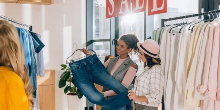three women shopping a clothes sale wondering if they'll have buyer's remorse after buying a pair of jeans
