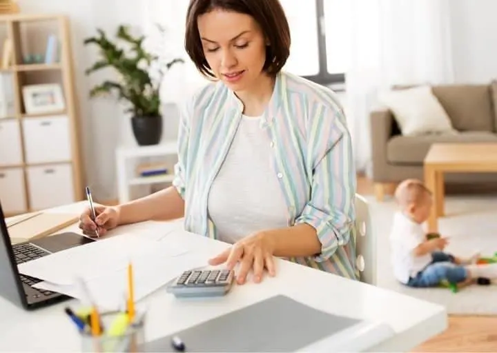 middle aged woman with calculator and laptop filing taxes at desk