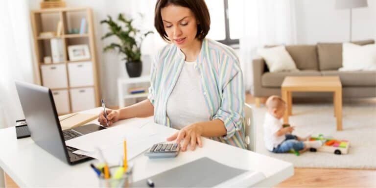 middle aged woman with calculator and laptop filing taxes at desk