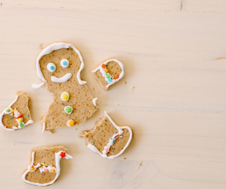 gingerbread man with icing and eyes, with all limbs broken off, and slightly put back together on wooden table