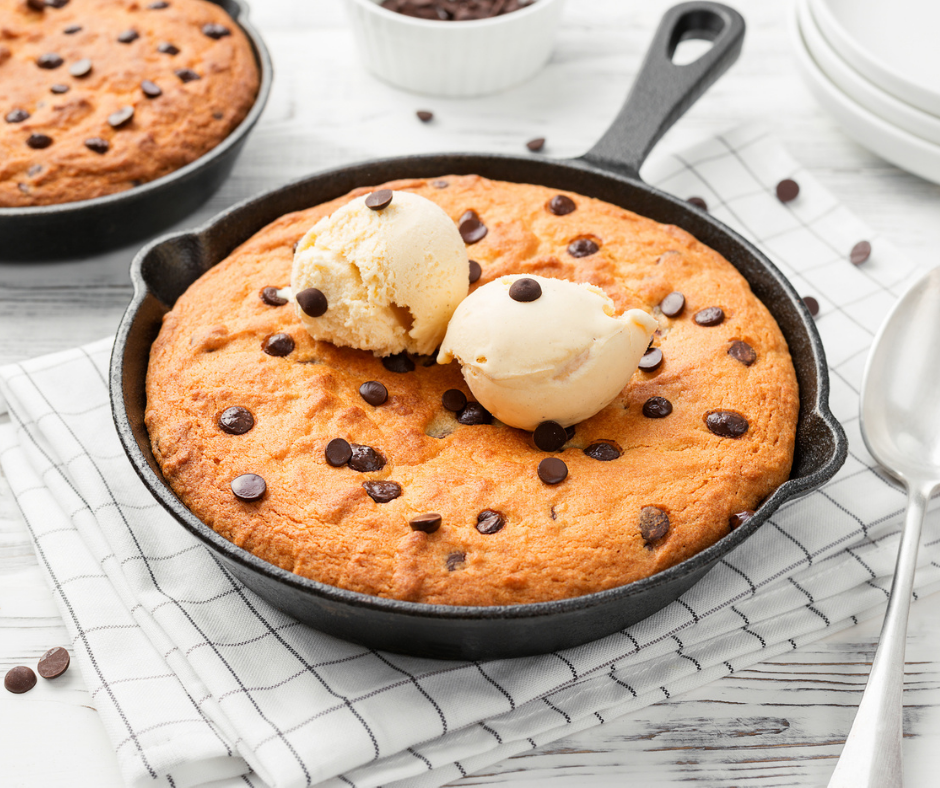 skillet chocolate chip cookie with vanilla ice-cream on top, on white marble table