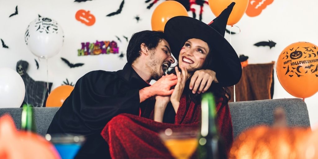 adult couple on couch dressed in Halloween costumes, giggling for things adults can do for halloween