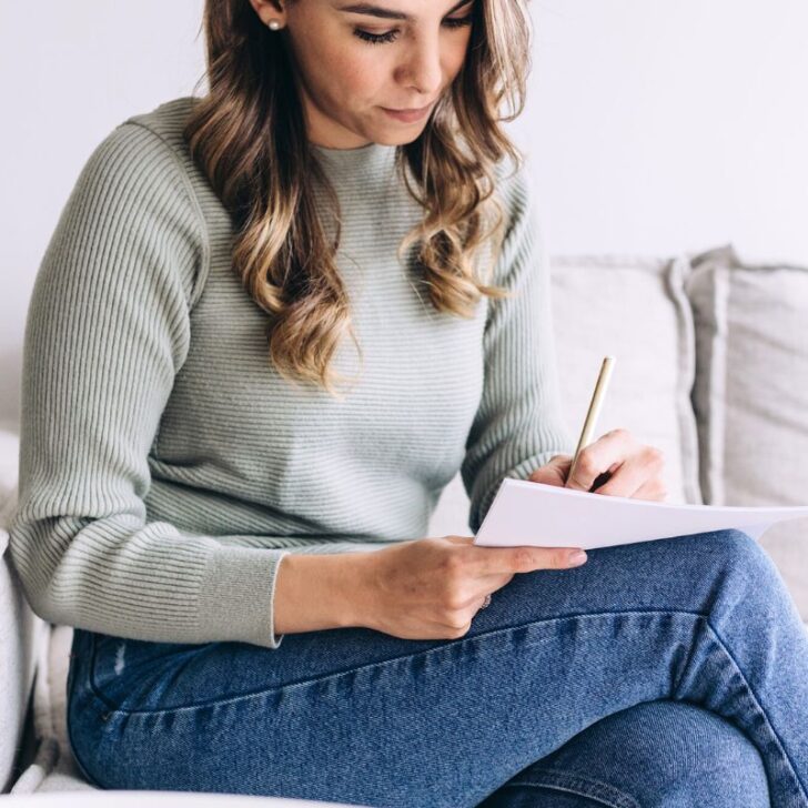 woman sitting on couch filling in savings goal tracker