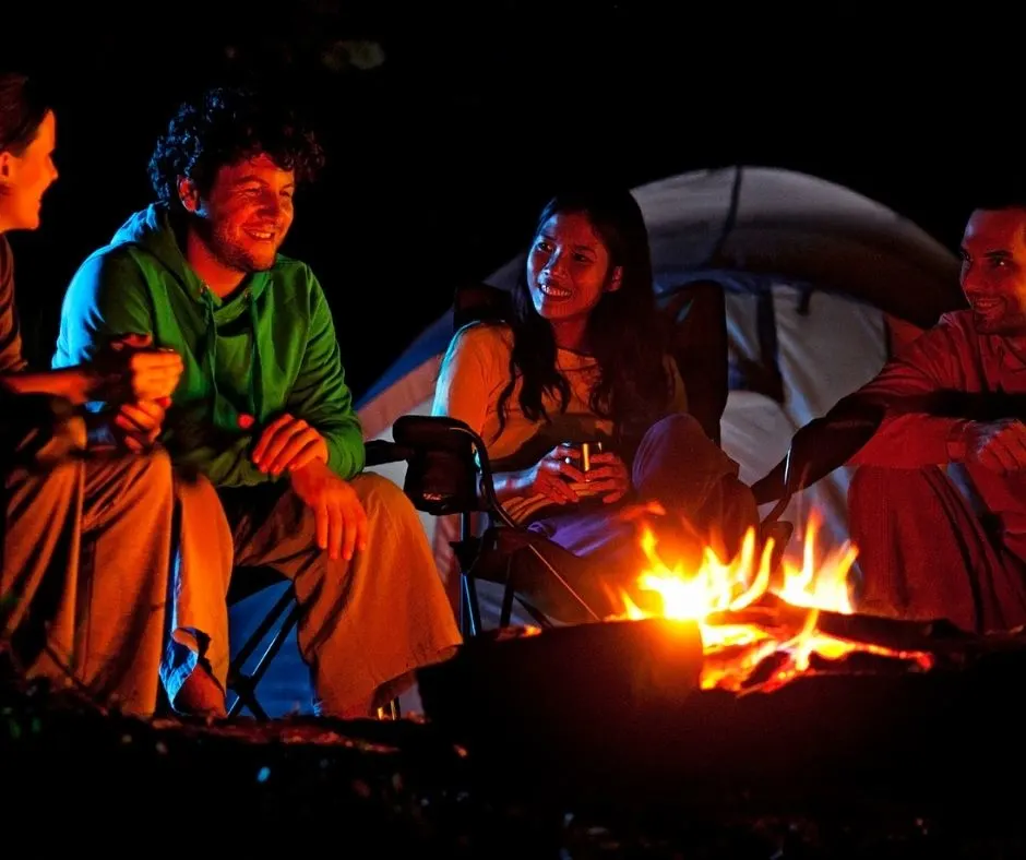 group of adults around a fire sharing spooky local ghost stories